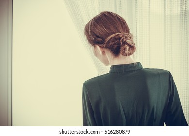 People And Solitude Concept. Alone Woman Looking Through Window Waiting Back View Indoor