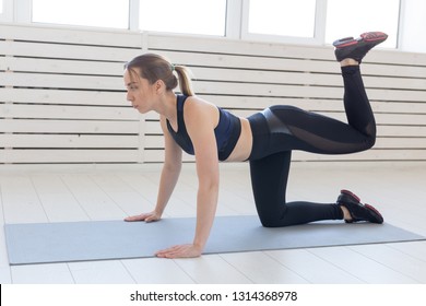 People, Sport And Fitness Concept - Slim Young Woman In Sportswear Doing Donkey Kick Exercise