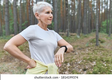 People, Sports, Health And Technology. Active Retired Female Wearing Smart Watch To Track Her Progress During Cardio Exercise Outdoors. Modern Mature Woman Walking In Park Using Fitness Tracker