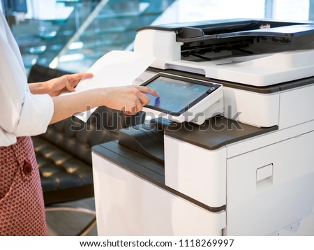 people stand by a copy machine  and hold on a paper for paper copy