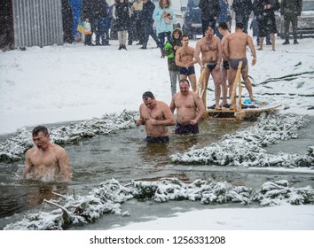 People Stand In Line In Front Of The Hole. The Man Dipped His Head. Swimming In The Ice Hole. The Rite Of Washing On The Eve Of The Feast Of The Epiphany. Ukraine. Belogorodka. January 18, 2018