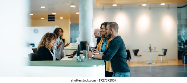 People standing in the hall of a municipal office and talking with the administrators. Municipality office reception with people being assisted by the receptionist. - Powered by Shutterstock