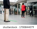 People standing in line front of bank/store due to coronavirus pandemic safety guideline.COVID-19 safe social distancing practice.Quarantine financial crisis,banking,loans.Spaced out queue.Crowd-limit