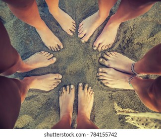 People are standing on the beach with feet in the circle. Picture is giving emotion of group of best friends having an amazing lovely time together.