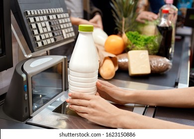 People standing in queue at checkout counter products on conveyor belt while cashier checking out bottle of milk close-up