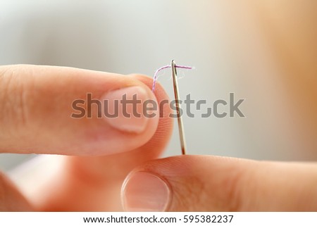 people, stitching, embroidery, needlework and sewing concept - hands of tailor woman threading needle