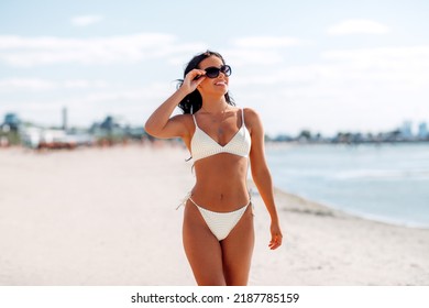 people, summer and swimwear concept - happy smiling young woman in bikini swimsuit on beach - Powered by Shutterstock