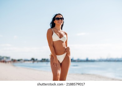 people, summer and swimwear concept - happy smiling young woman in bikini swimsuit on beach - Shutterstock ID 2188579017