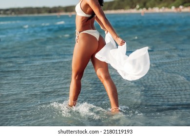 people, summer and swimwear concept - young woman in bikini swimsuit with cover-up on beach - Powered by Shutterstock