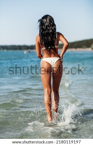 people, summer and swimwear concept - young woman in bikini swimsuit on beach