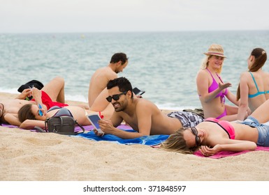 People Sunbathing On The Beach Near The Sea