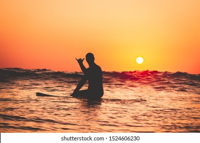People surfing at the beach at sunset