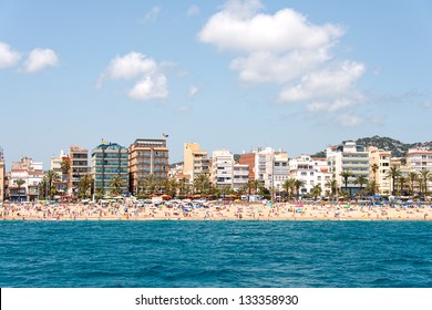 People swim and sunbathe at the city beach of Lloret de Mar, Spain