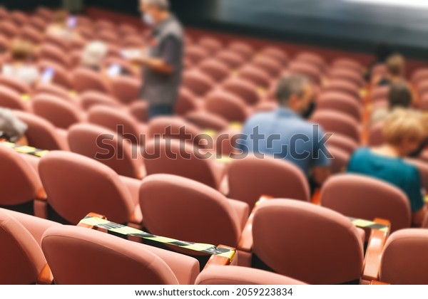 people\
taking seats while observing social\
distancing