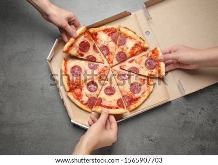 People taking slices of tasty pepperoni pizza at grey table, top view