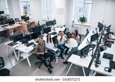 People talking and working together in the modern office near computers.