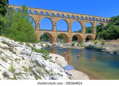 People Tanning Ang Bathing Near Pont Du Gard - An Ancient Aqueduct Across The River Gardon Near Nimes, France