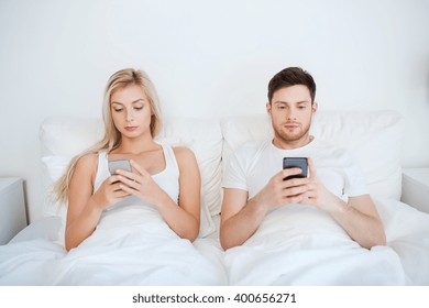 people, technology, internet and communication concept - couple with smartphones in bed - Powered by Shutterstock