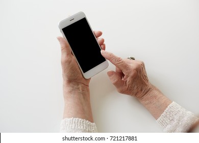 People, technology, job, occupation and age. Close up shot of senior woman hands holding smart phone with copy space. Modern retired elderly female using wifi on mobile, earning money via internet