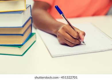 people, technology, learning and education concept - close up of african american young woman hand writing to notebook with books at home - Powered by Shutterstock