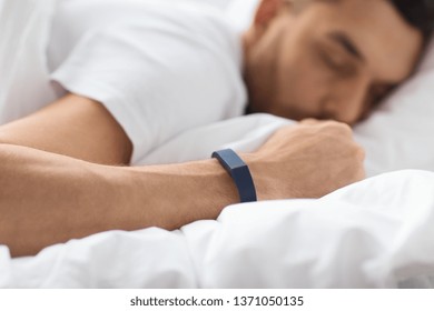 People, Technology And Rest Concept - Close Up Of Man With Activity Tracker Sleeping In Bed