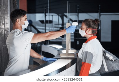 People, temperature and face mask for health at gym with safety compliance, thermometer exam and covid19 risk. Man, monitor and client with healthcare, virus emergency and check results of ppe policy - Powered by Shutterstock