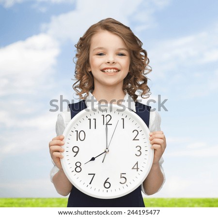 people, time management and children concept - smiling girl holding big clock showing 8 o'clock