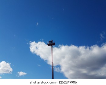 People At The Top Of A Cherry Picker Or Tower And Blue Sky With Cloud