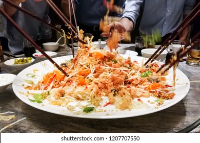 People tossing yee sang or yusheng during Chinese New Year , traditional practice in Malaysia and Singapore for luck and prosperity