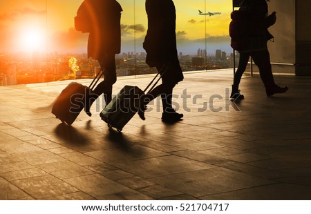  people and traveling luggage walking in airport terminal building with sun set sky at urban scene and air plane flying background