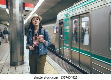 People In Underground Platform Transit In Osaka Subway Station On Commute With Train. Asian Travel Woman Hold Mobile Phone Exiting Boarding With Man Commuter And Conductor Crew Inside Metro.