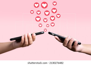 People use mobile phone sending heart to each other. Love and connection concept using telephone application on pink background. - Shutterstock ID 2130276482