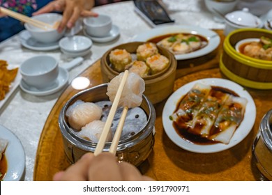 People Using Chopsticks And Having Hong Kong Dimsum In Restaurant