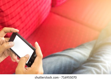 People using smartphone while sitting on red sofa at his home