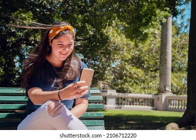 People Vaccinated Against Covid 19 Can Be Without A Mask In City Parks, Like This Young Caucasian, Hispanic Latin Girl Smiling Talking To Her Family Outside On A Video Call With Her Phone In The Park.