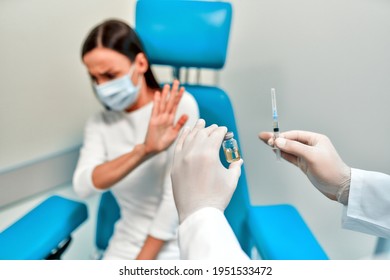 People Vaccination Phobia Concept. Male Doctor Trying To Give Vaccine To A Scared Patient. Angry And Distrustful Patient Refuses To Receive It. Stop Vaccinations. Say No To The Coronavirus Vaccines.