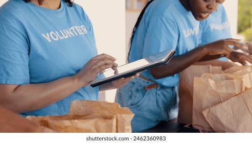 People volunteering, tablet and food donation in community service, poverty support and NGO checklist. Nonprofit, hands or group packaging groceries, planning package or helping for charity project - Powered by Shutterstock