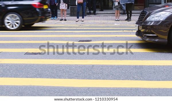 People\
waiting to cross street, pedestrian crossing on busy road, detail\
of the legs of a crowd, city daily\
traffic.