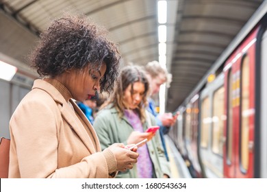 Menschen, die auf den U-Bahn-Zug in London warten - multiethnische Gruppe von Leuten, die ihre Telefone anschauen und auf einem U-BahnBahnhof in London warten - Reise-, Lifestyle- und Technologiekonzepte