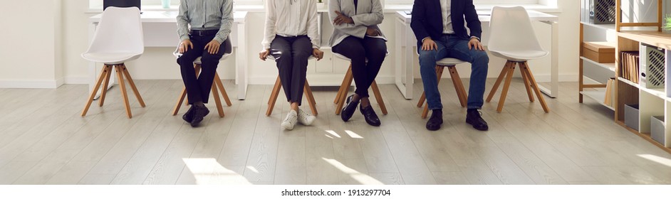 People are waiting in the waiting room. Cropped image of the legs of various people sitting on chairs and waiting their turn for an interview. Concept of employment, clients and human resources. - Shutterstock ID 1913297704
