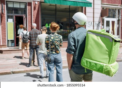 People waiting, standing in line, respecting social distancing to enter takeout restaurant or to collect purchases from the pickup point during lockdown. Selective focus. Horizontal shot - Powered by Shutterstock