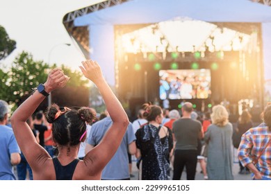 People waiting for a summer music festival to start in front of the stage at sunset
