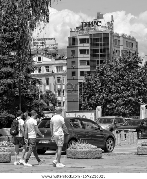 People walk in the city. Building of PWC\
company in Sofia. Insurance, advisory, tax service. Black and White\
Photography. Bulgaria, Sofia – June 10, 2017\
