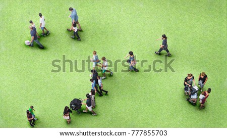people walk on the greenfield grass landscape with the teenage young man and the group of family with little child. (Aerial urban city photo)