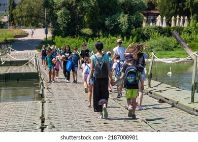 People walk over Serbian Army pontoon bridge connecting Zemun municipality of Belgrade with the Lido Beach in the Great War island on Danube river. Belgrade, Serbia 25.07.2022
