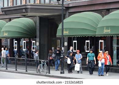 People Walk Past The World Famous Harrods Department Store On June 16, 2015 In London, UK. Opened In 1840 The Landmark Luxury Department Store Covers 80,000 Sqm Of Retail Space In Central London.