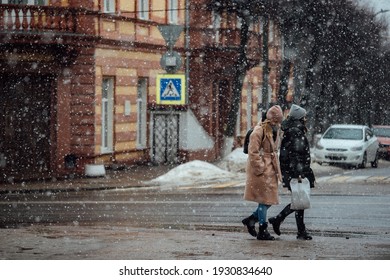 People Walk Through The City In A Snowstorm. Take Shelter From The Strong Wind. Climate Change And Winter Cooling