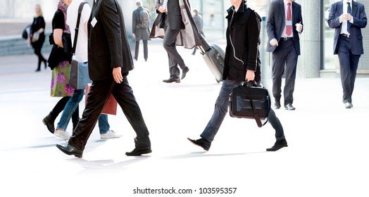 People walking against the light background of an urban landscape. Motion blur. - Shutterstock ID 103595357