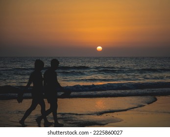 People Walking Along The Shore Of The Beach At Sunset. Holidays On The Beach Of Conil De La Frontera, Cadiz, Spain. Walk Through The Mediterranean Sea.