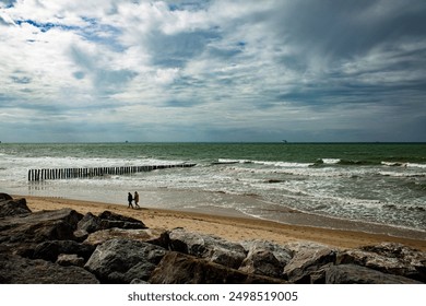 people walking at the beach under dramatic sky